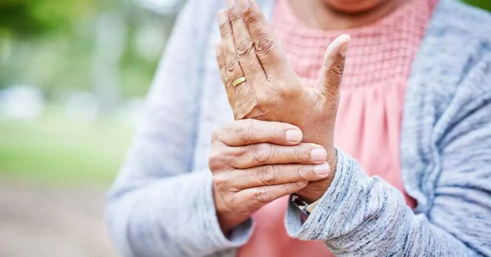 Person holding wrist, possibly in pain, OT support for arthritis in hands & wrists can help.