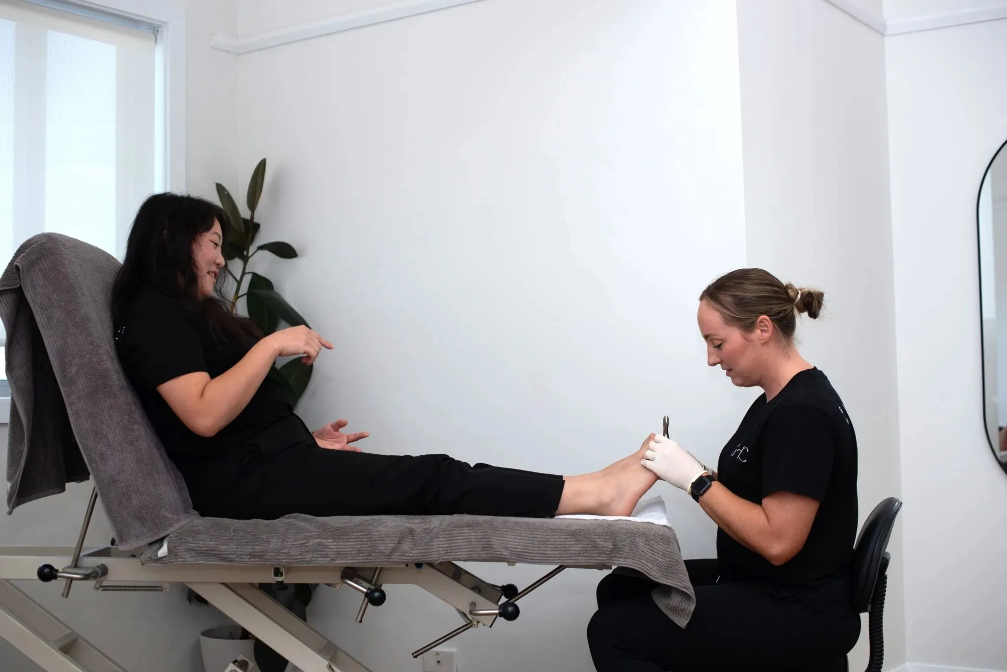 Podiatrist treating a patient's foot while they rest on a treatment couch